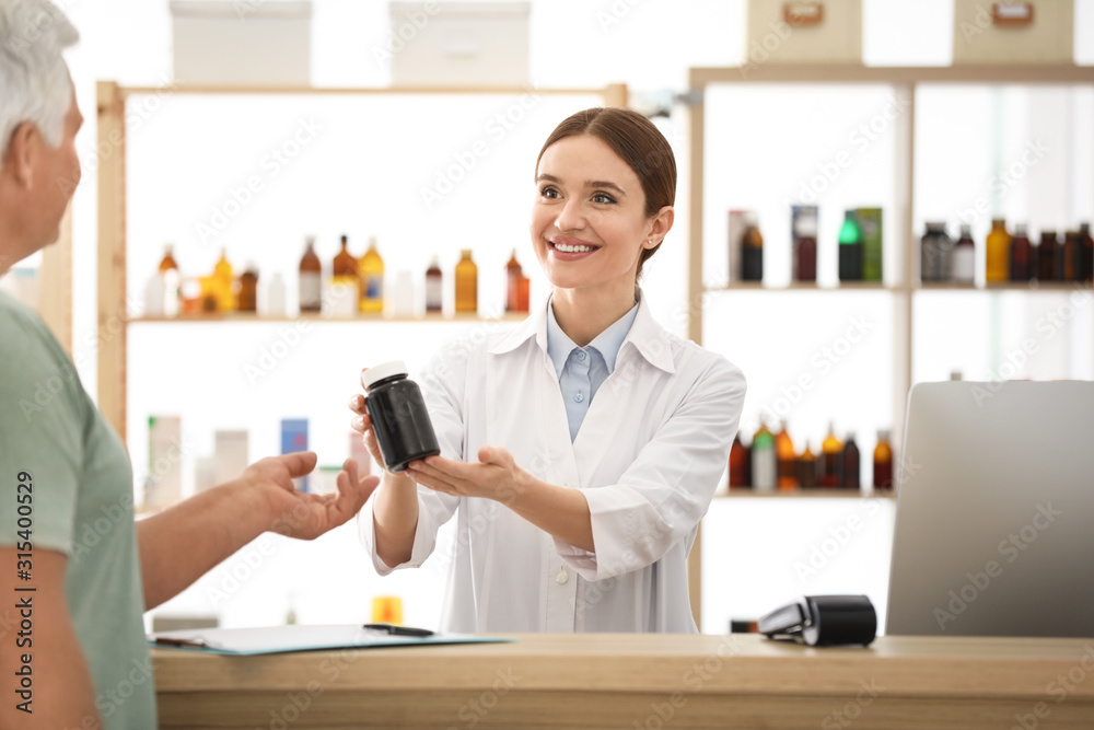 Pharmacist giving medicine to customer in drugstore Pharmacist giving medicine to customer in drugstore