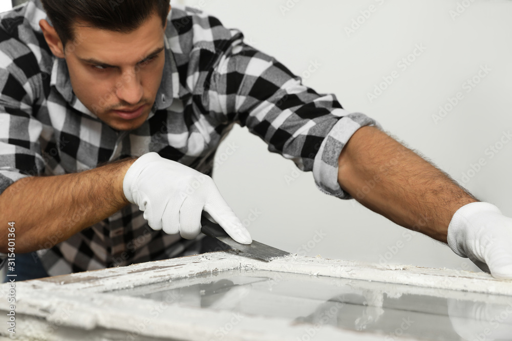 Man repairing old damaged window at table indoors Man repairing old damaged window at table indoors