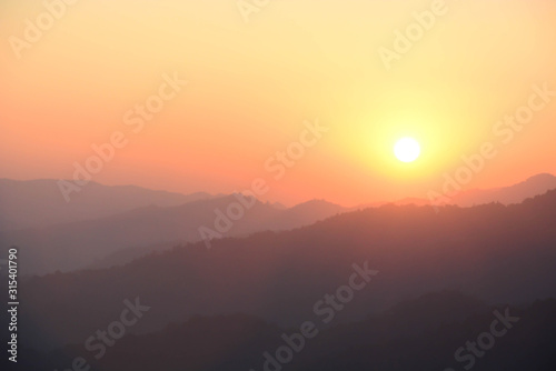 Blurred sunset silhouette mountain landscape background with orange sky.