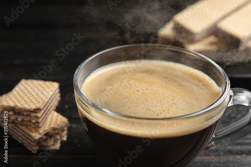 Delicious coffee and wafers on black table, closeup