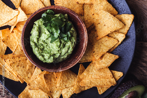 Mexican traditional food, guacamole sauce, ingredients  avocado, cilantro, lime and tortilla corn chips