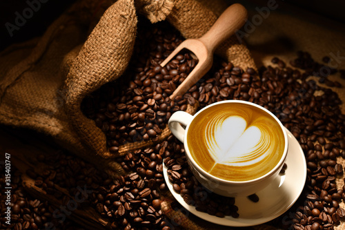 Cup of coffee latte with heart shape and coffee beans on old wooden background © amenic181