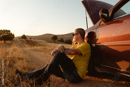 Man leaning in broken car in countryside photo