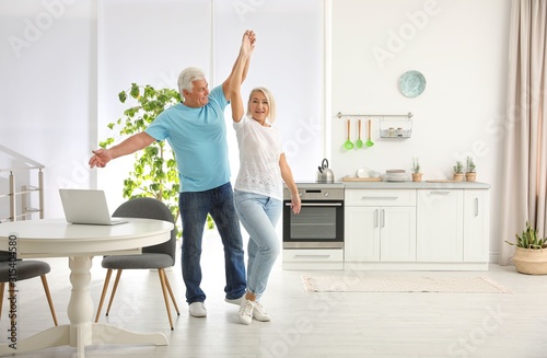 Happy mature couple dancing together in kitchen