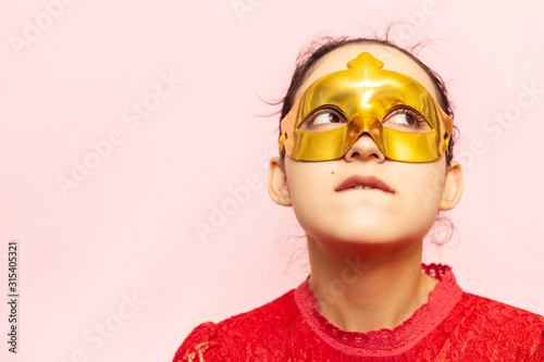 Portrait of beautiful woman in evening dress and golden masquerade mask. Valentines day, Carnival, Festive Ball, Birthday celebration concept. Facial expressions of young female