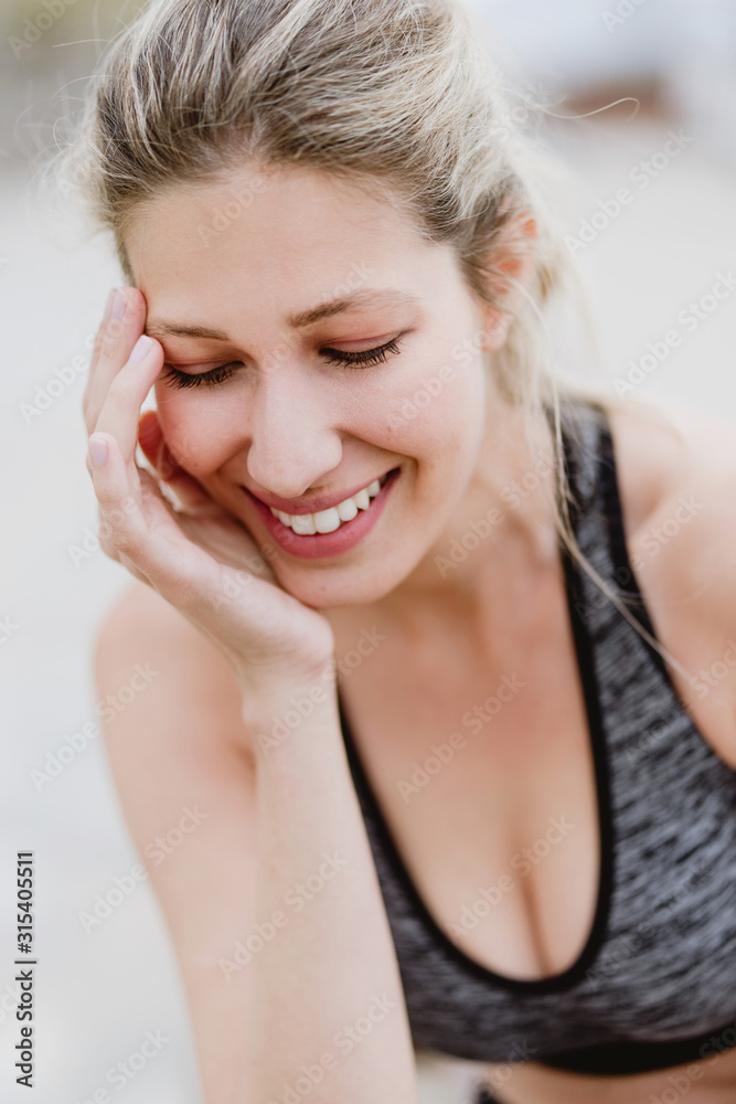 Content young with closed eyes female athlete in stylish sports outfit leaning hands on knees while training Content young with closed eyes female athlete in stylish sports outfit leaning hands on knees while training