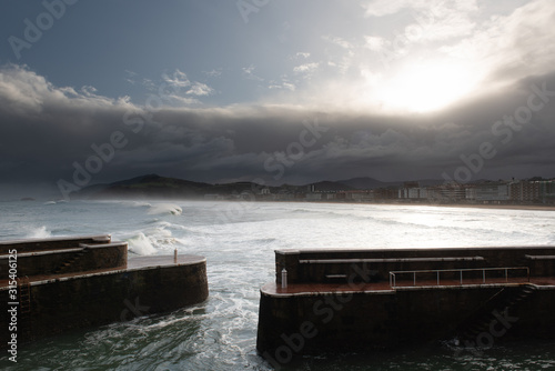 Rock breakwater with raging sea on cloudy weather