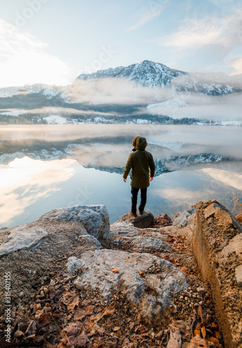 man enjoys the perfect nature view of the winter lake and mountains.