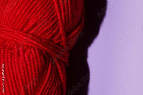 Red skein of thread for knitting on a purple background  copy space. macro