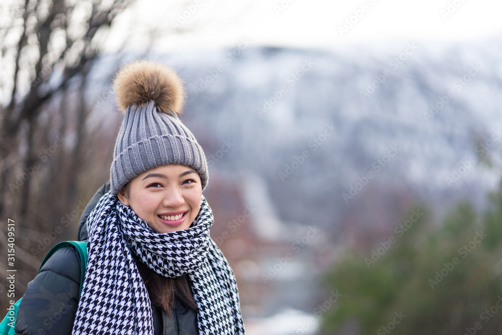 Cheerful Asian female traveler in warm clothing smiling and looking at camera with mountain on blurred background at Tromso in Norway Cheerful Asian female traveler in warm clothing smiling and looking at camera with mountain on blurred background at Tromso in Norway