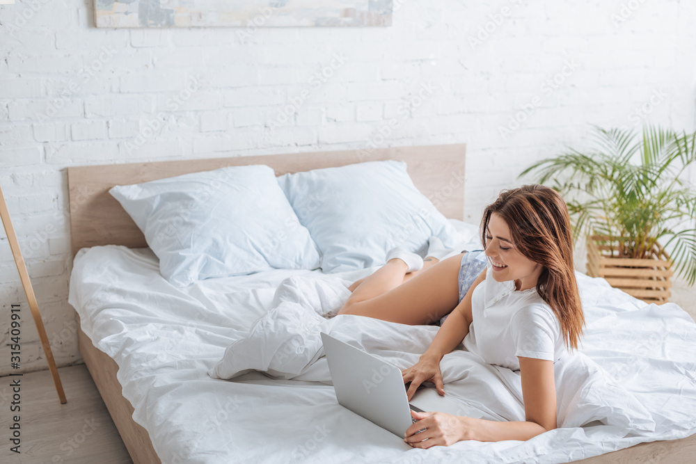 cheerful young woman using laptop while chilling in bedroom cheerful young woman using laptop while chilling in bedroom