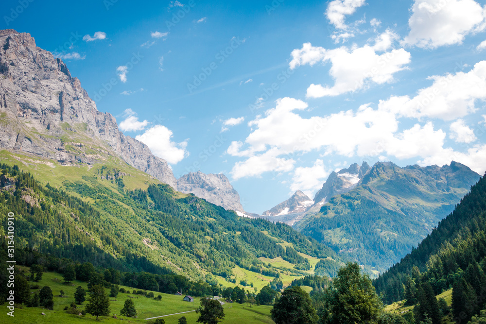 Scenery picturesque view of houses on green meadows in alps peaks mountain in Switzerland Scenery picturesque view of houses on green meadows in alps peaks mountain in Switzerland