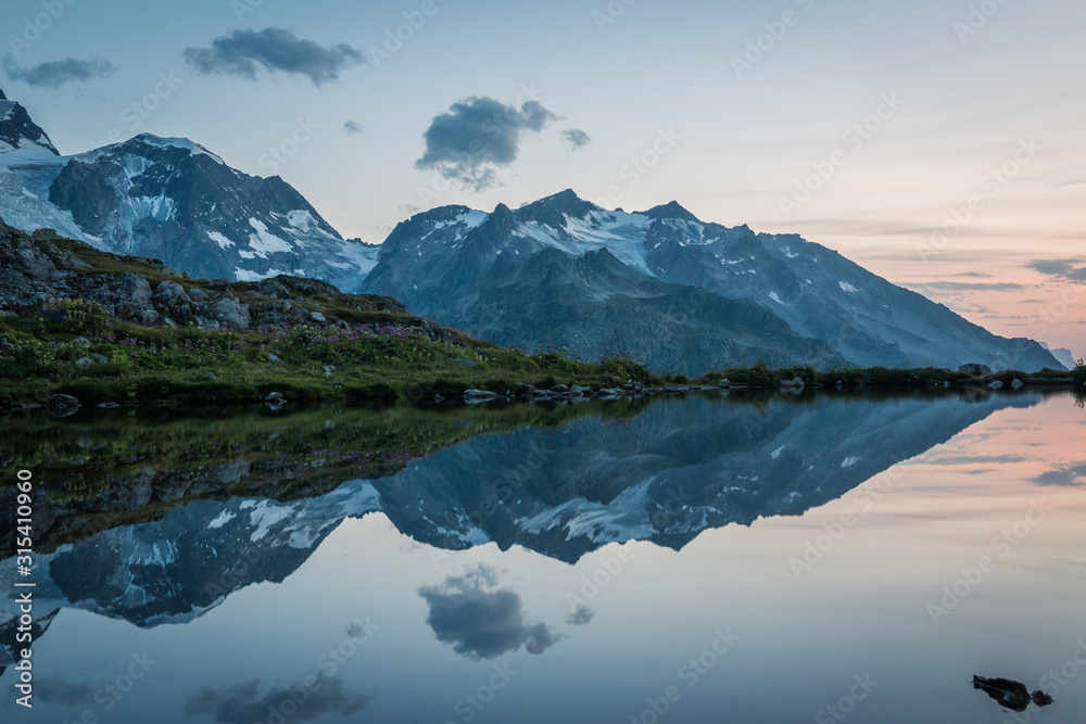 Empty coast of calm lake in snowy mountains reflecting sky in Switzerland Empty coast of calm lake in snowy mountains reflecting sky in Switzerland