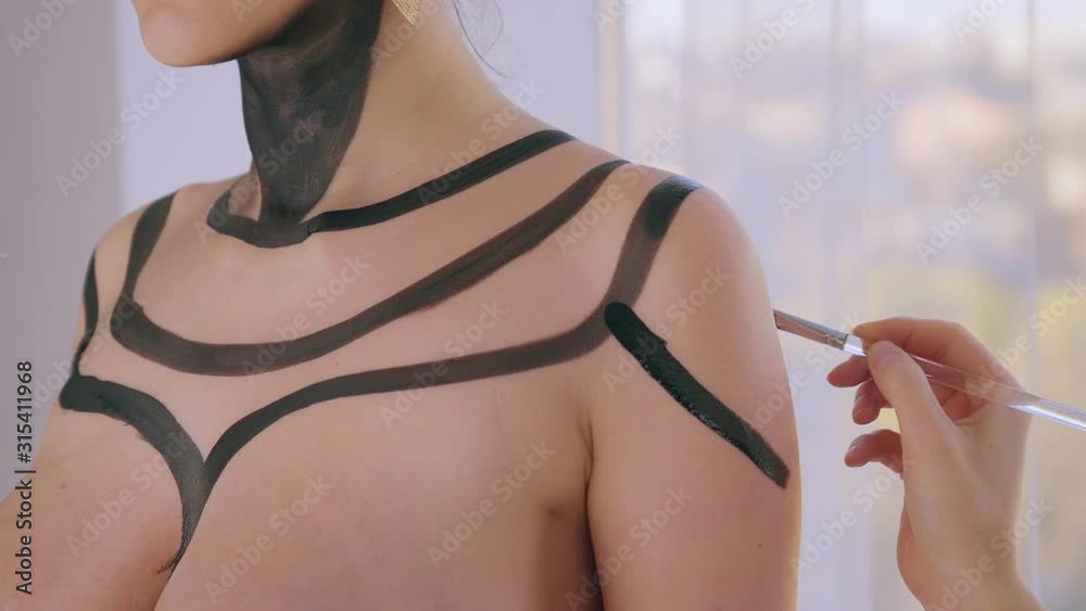 Body art. Bodypaint master in work in art studio, paints a model for a photo shoot