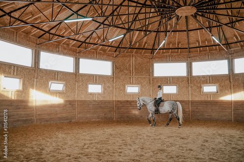 Rider riding dapple gray horse in round arena photo