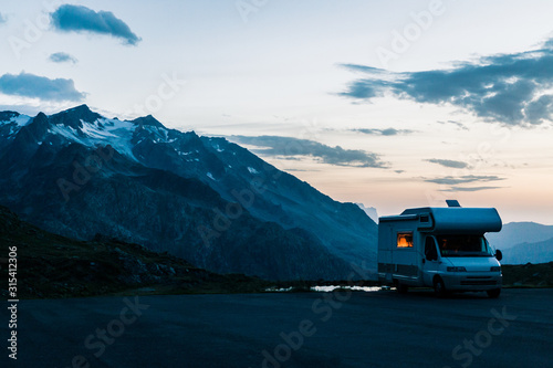 White camper moving on road along lake with crystal water in twilight in Switzerland 