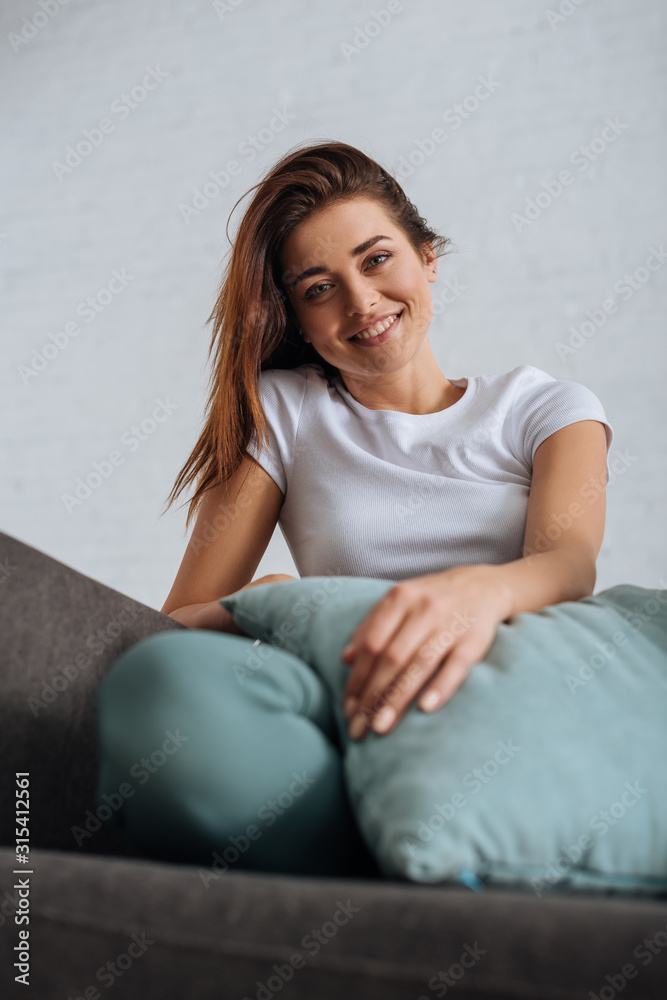 selective focus of cheerful girl looking at camera while chilling on sofa selective focus of cheerful girl looking at camera while chilling on sofa