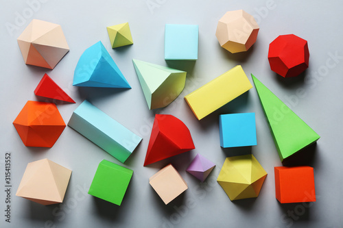 Colorful paper geometric figures on grey background