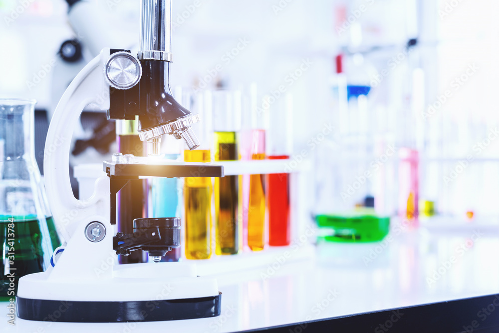 Microscope and test tubes with lab glassware in laboratory background, research and Scientific concept Microscope and test tubes with lab glassware in laboratory background, research and Scientific concept