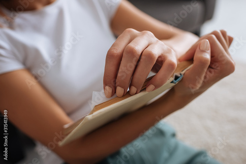 cropped view of young woman holding book while chilling at home © LIGHTFIELD STUDIOS