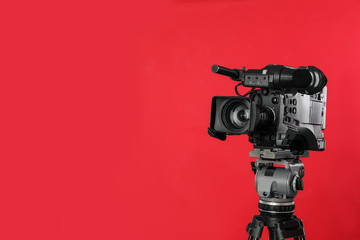 Modern professional video camera on red background. Space for text