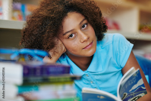 Vászonkép Horizontal portrait shot of beautiful teengirl sitting at school library table w