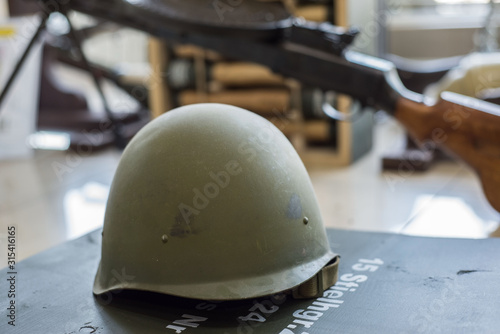 green military helmets, stand in the arms store on the background of machine guns and machine guns. photo