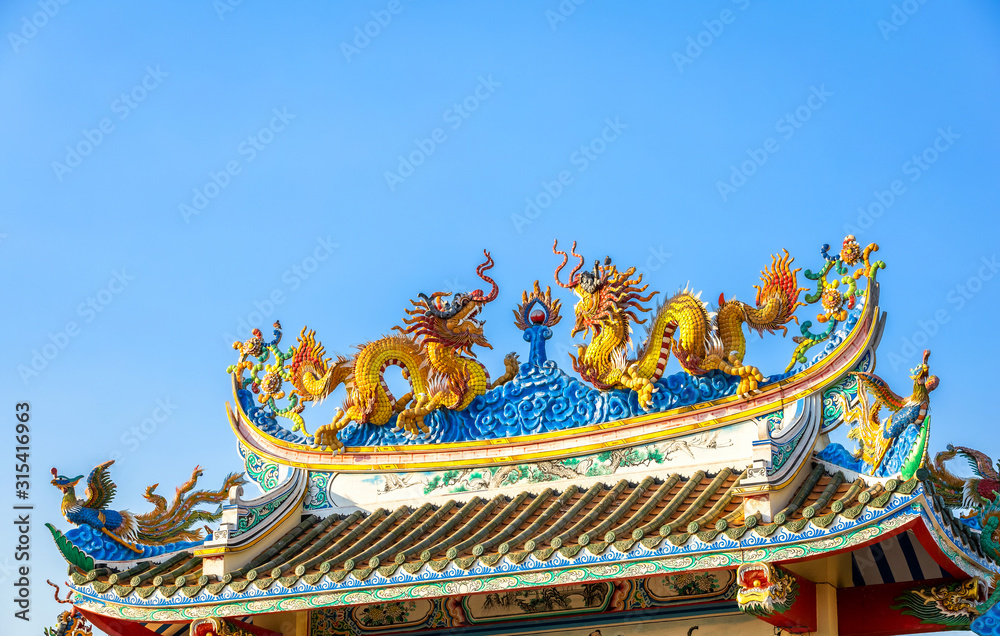 Beautiful Elegant double golden dragon statue on the roof of on a temple for Chinese New Year Festival at Chinese shrine with blue sky.