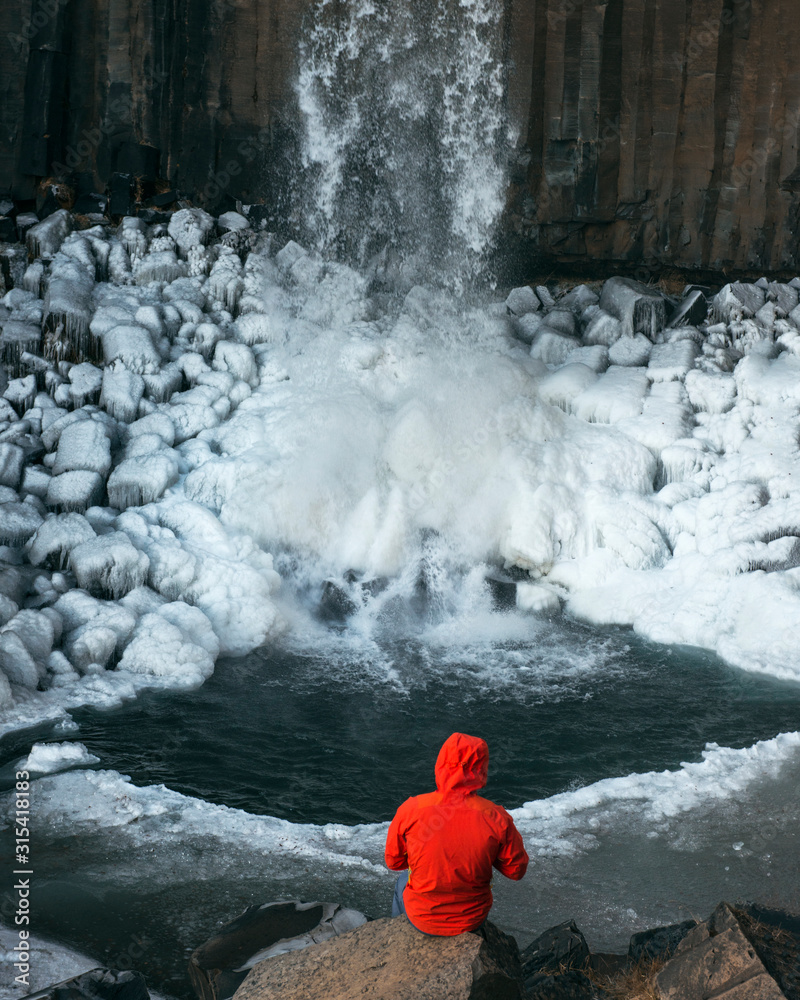 Fototapeta premium chico mirando cascada con abrigo rojo