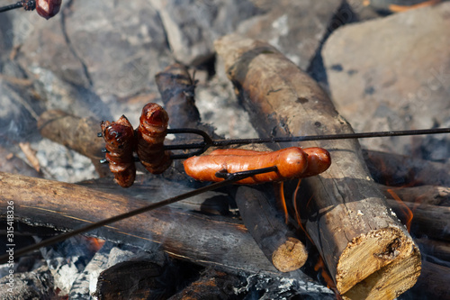 Grilling sausages with BBQ fork on open fire