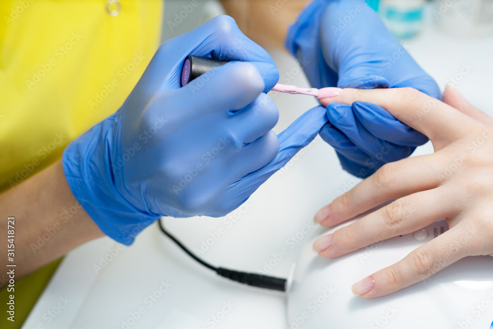 Nail care. Manicure in the salon. The master manicures the girl, beauty and health. Manicure process. Master in mask and gloves. Nail polish. Nail care. Manicure in the salon. The master manicures the girl, beauty and health. Manicure process. Master in mask and gloves. Nail polish.