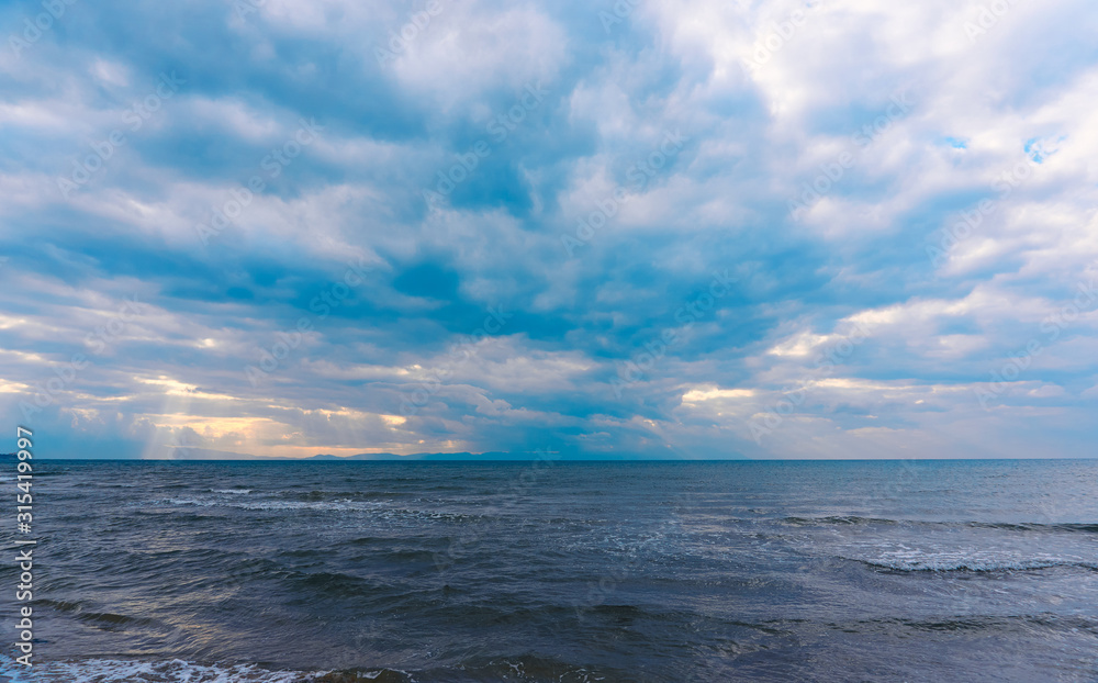 Sunlight beams through the clouds on the beach in a winter day