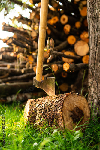 Wooden background. Firewood stack for the background. A lot of cutted logs. Stack of sawn logs. Natural wooden decor background. Pile of chopped fire wood prepared for winter. photo with axe.
