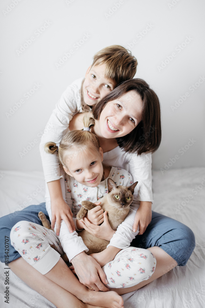 Mother with two kids and a cat sitting on bed Mother with two kids and a cat sitting on bed