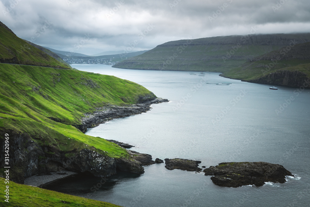 Obraz premium Dramatic view of green hills of Vagar island and Sorvagur town on background. Faroe islands, Denmark. Landscape photography