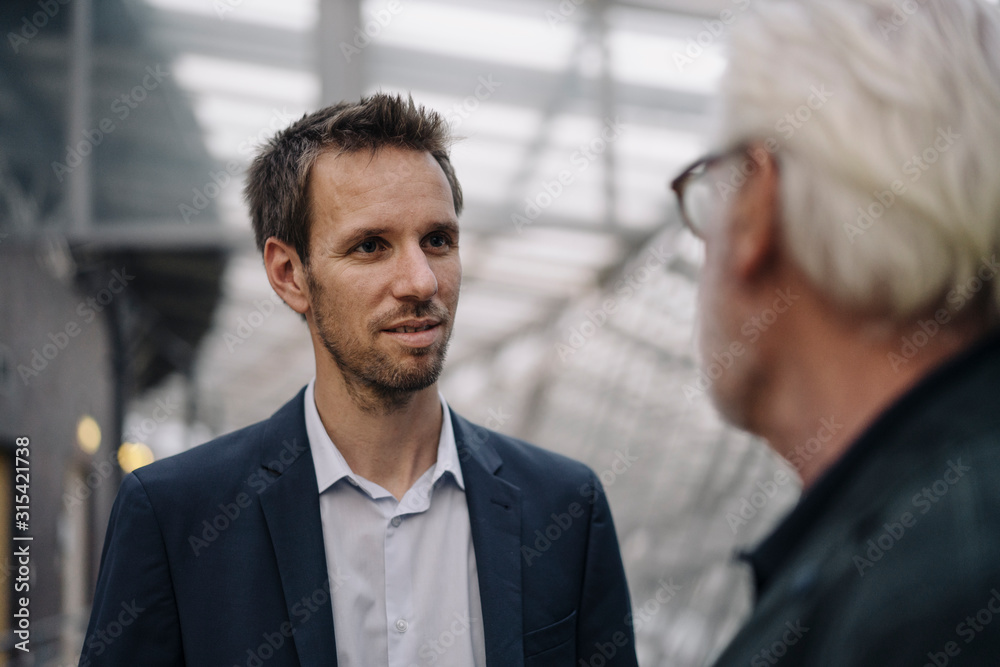 Portrait of businessman looking at senior colleague in office