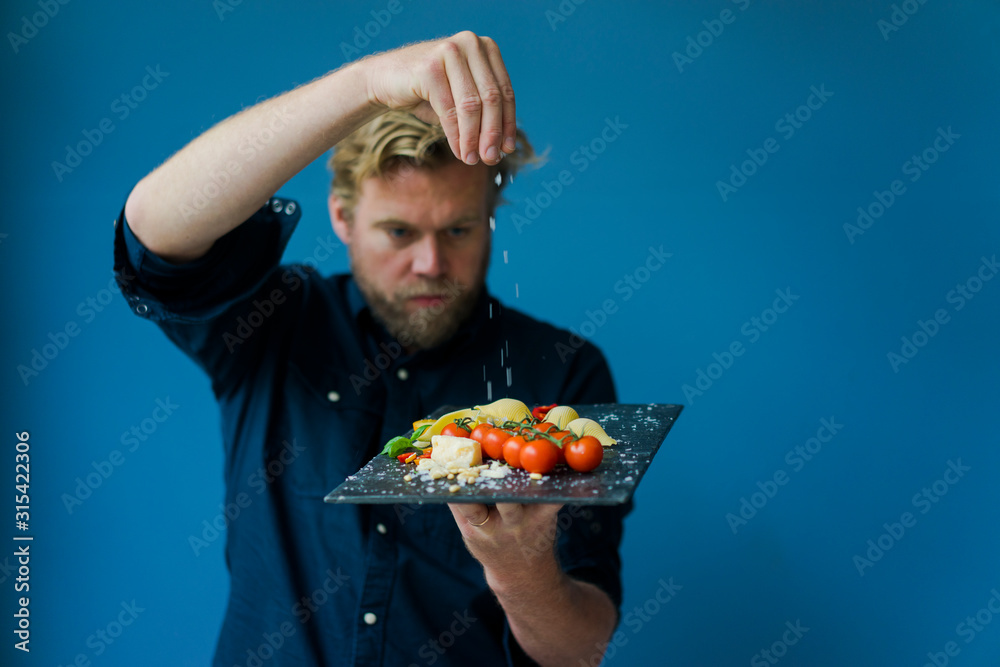 Man seasoning platter with cheese and tomatoes Man seasoning platter with cheese and tomatoes