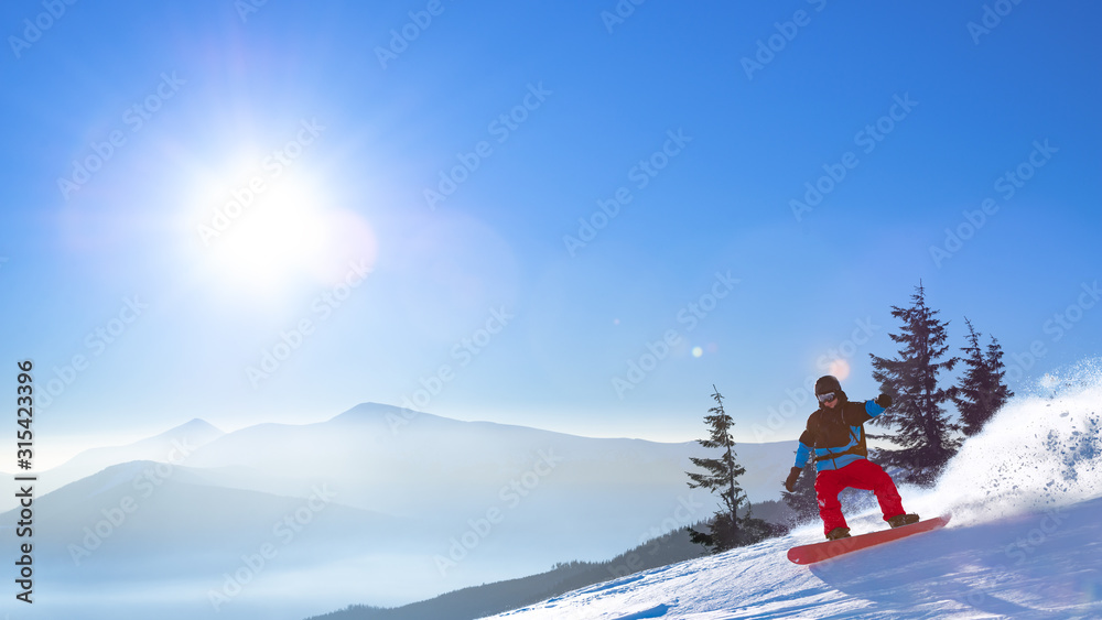 Snowboarder Riding Red Snowboard on the Slope in the Morning Mountains at Sunny Weather. Snowboarding and Winter Sports