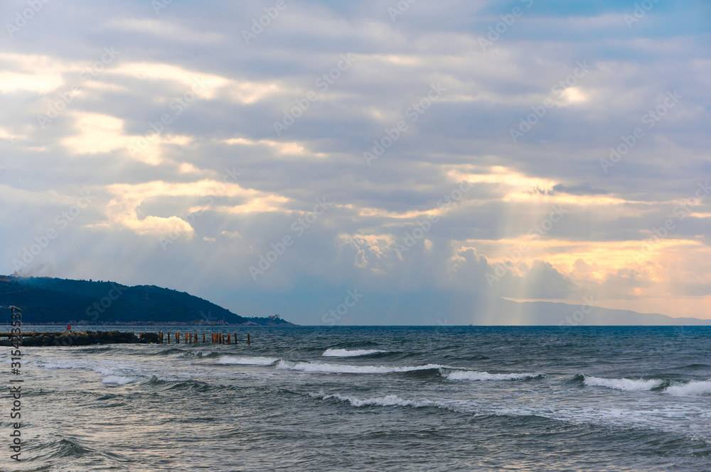 Sunlight beams through the clouds on the beach in a winter day