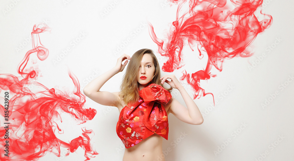 Chinese style girl model fashion photo on white background. Asian stylized makeup. Traditional fabric pattern. Red smoke in shape of dragons