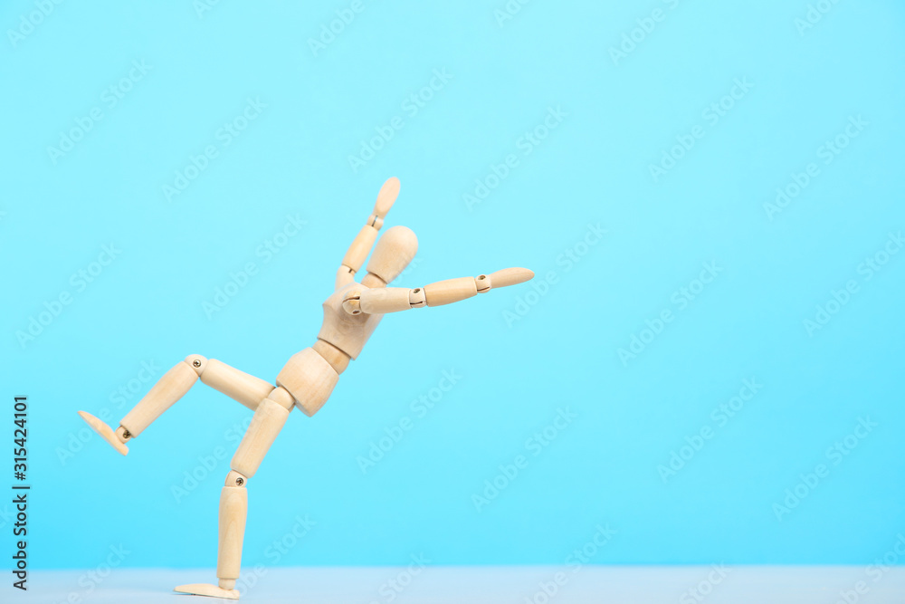 Wooden figure falling on blue background