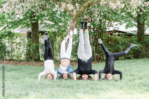 Mother with three triplet daughters doing a headstand on a meadow