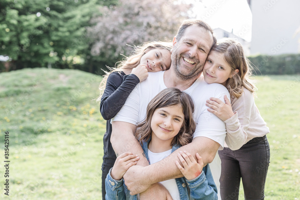 Portrait of happy father with three triplet daughters on a meadow Portrait of happy father with three triplet daughters on a meadow