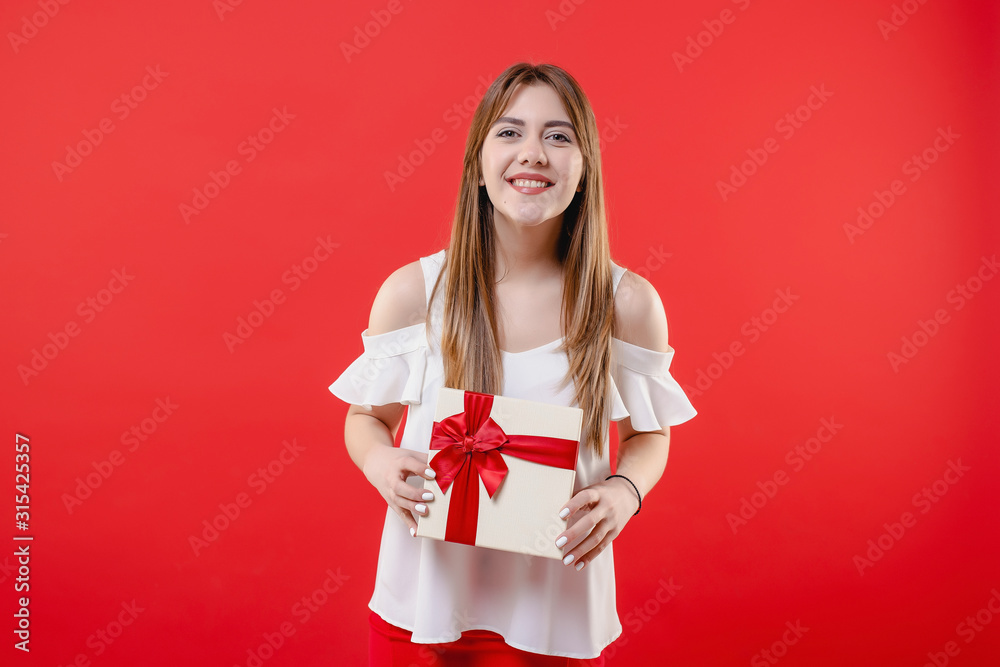 excited woman with gift box wearing white blouse isolated on red background excited woman with gift box wearing white blouse isolated on red background