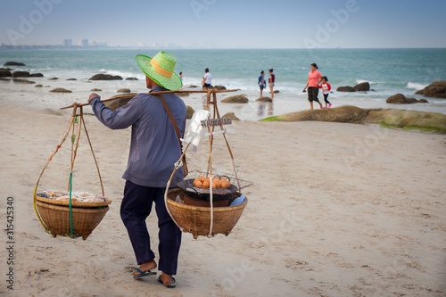 People enjoy on the beach together with local food sales man. 2015 February Thailand Hua Hin. 