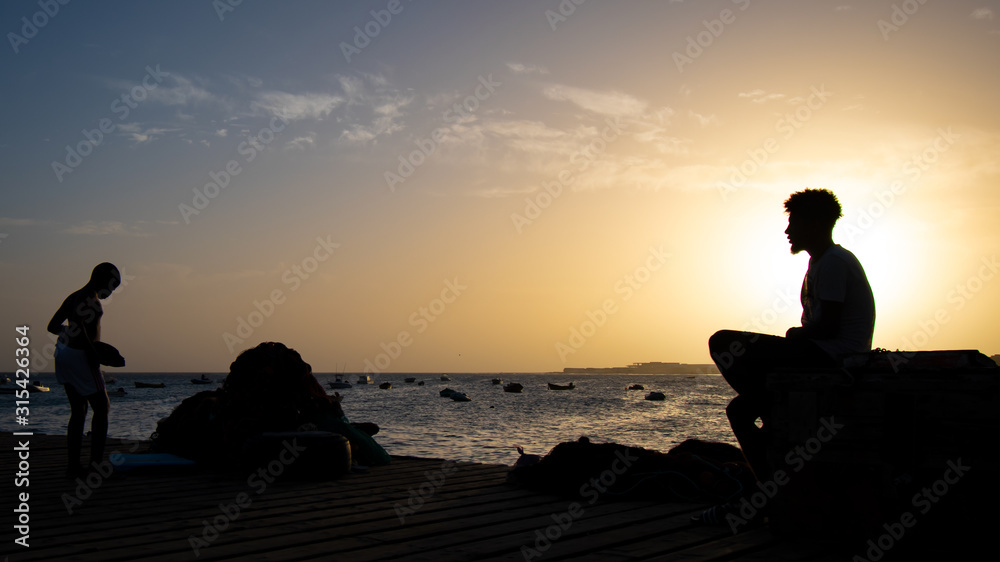 silhouette of man sitting on the beach at sunset
