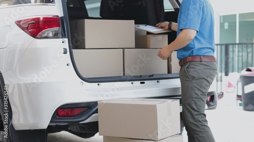 In-Home Delivery concept. Delivery Man unloading his shipping van with  parcel post in cardboard boxes and checking stock of parcel post before delively to costomer photo