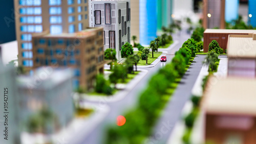 modern generic contemporary style miniature model of glass buildings and streets with tilt-shift focus technique - focus is on the red car in the middle of the street