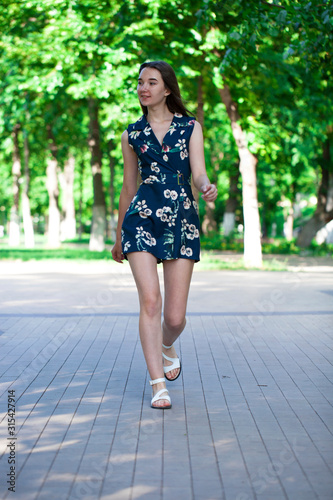Young beautiful woman in a blue short dress walking on the road © Andrey_Arkusha