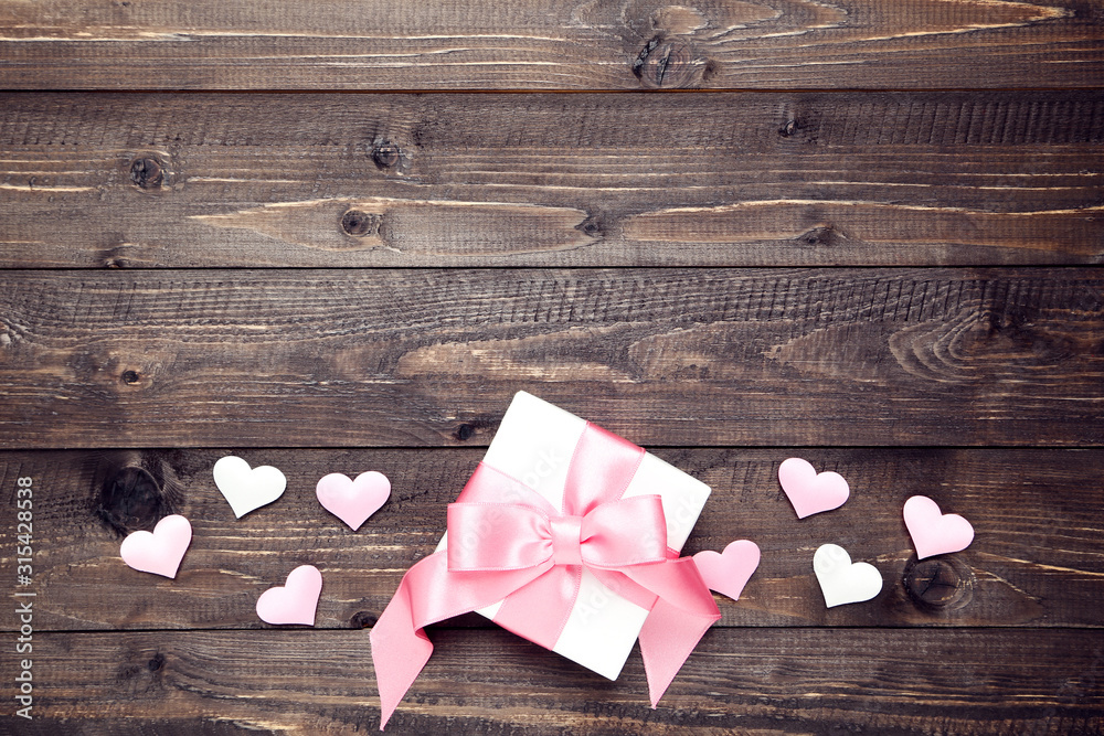 Gift box with ribbon and hearts on wooden table Gift box with ribbon and hearts on wooden table